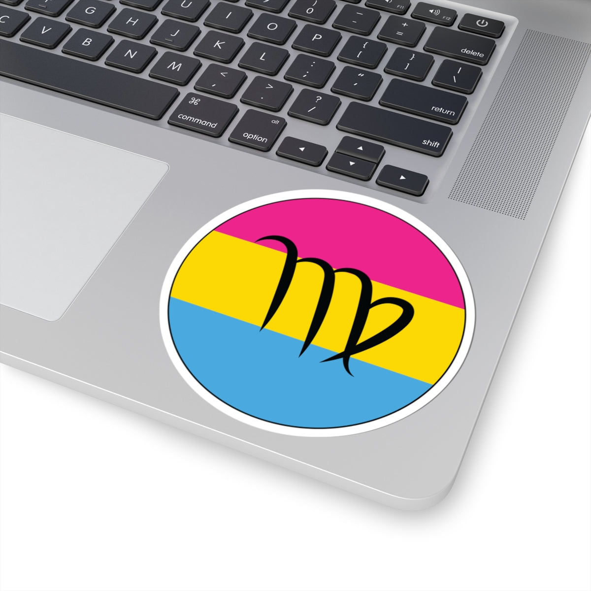 Close-up of the bottom right corner of a silver laptop featuring a 4 inch by 4 inch circular zodiac sticker with a centered Virgo glyph on a Pansexual pride flag style background applied to the surface.