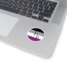 Close-up of the bottom right corner of a silver laptop featuring a 2 inch by 2 inch circular zodiac sticker with a centered Capricorn glyph on an Asexual pride flag style background applied to the surface.