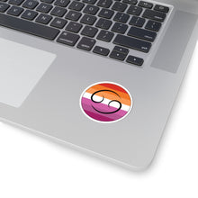 Close-up of the bottom right corner of a silver laptop featuring a 2 inch by 2 inch circular zodiac sticker with a centered Cancer glyph on a Lesbian pride flag style background applied to the surface.