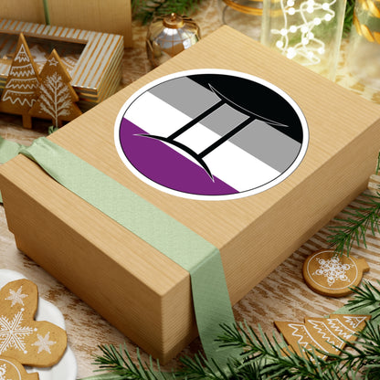 Gift box with a green ribbon on a festive background with cookies and Christmas decorations. Gemini Asexual pride sticker centered on the box.