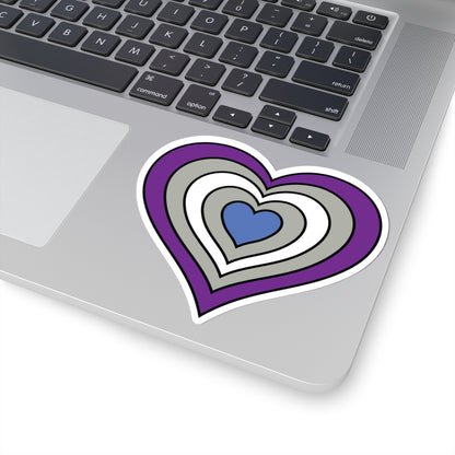 Close-up of the bottom right corner of a silver laptop featuring a 4 inch by 4 inch pride flag heart sticker in a Greysexual flag style applied to the surface.