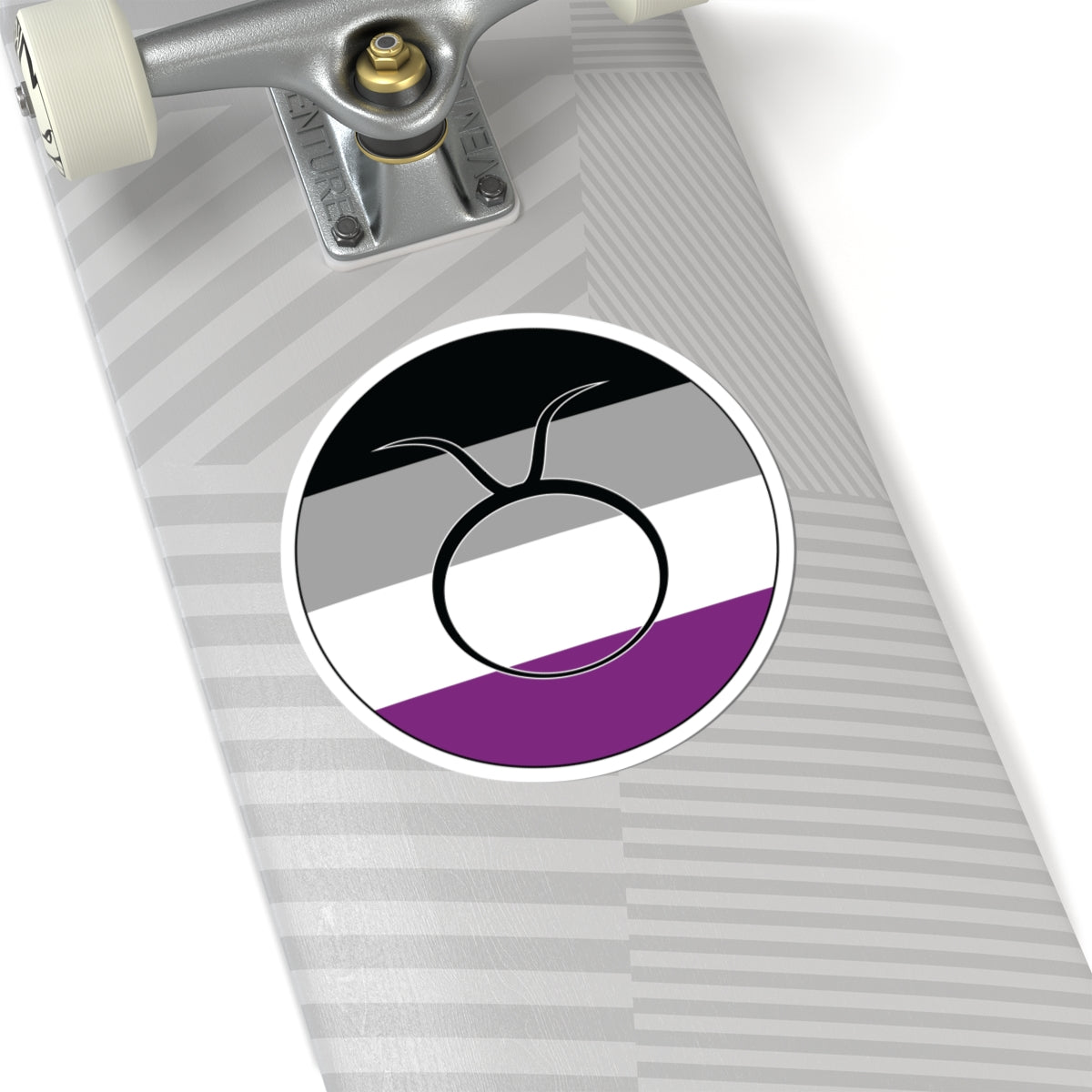 Close-up of the bottom of a silver skateboard featuring a 6 inch by 6 inch circular zodiac sticker with a centered Taurus glyph on an Asexual pride flag style background applied to the surface.