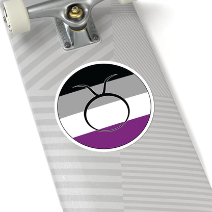 Close-up of the bottom of a silver skateboard featuring a 6 inch by 6 inch circular zodiac sticker with a centered Taurus glyph on an Asexual pride flag style background applied to the surface.