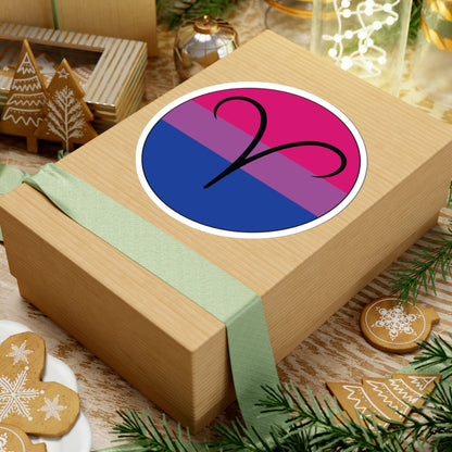 Gift box with a green ribbon on a festive background with cookies and Christmas decorations. Aires Bisexual pride sticker centered on the box.