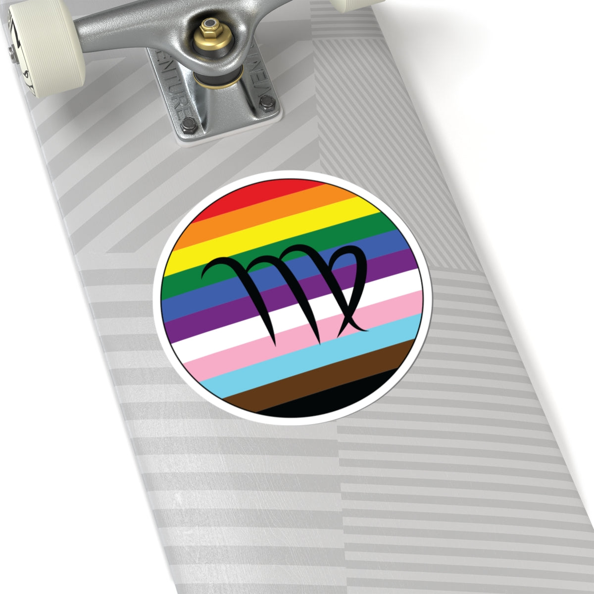 Close-up of the bottom of a silver skateboard featuring a 6 inch by 6 inch circular zodiac sticker with a centered Virgo glyph on a progress pride flag style background applied to the surface.