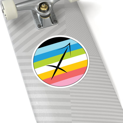 Close-up of the bottom of a silver skateboard featuring a 6 inch by 6 inch circular zodiac sticker with a centered Sagittarius glyph on a Queer pride flag style background applied to the surface.