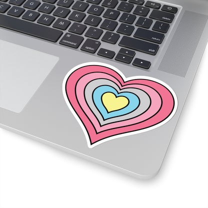 Close-up of the bottom right corner of a silver laptop featuring a 4 inch by 4 inch pride flag heart sticker in a Genderflux flag style applied to the surface.