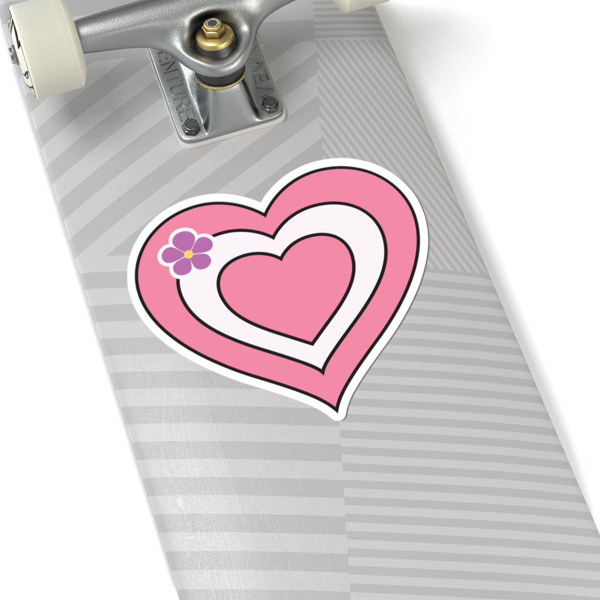 Close-up of the bottom of a silver skateboard featuring a 6 inch by 6 inch pride flag heart sticker in a Sapphic pride flag style applied to the surface.