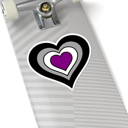 Close-up of the bottom of a silver skateboard featuring a 6 inch by 6 inch pride flag heart sticker in an Asexual flag style applied to the surface.