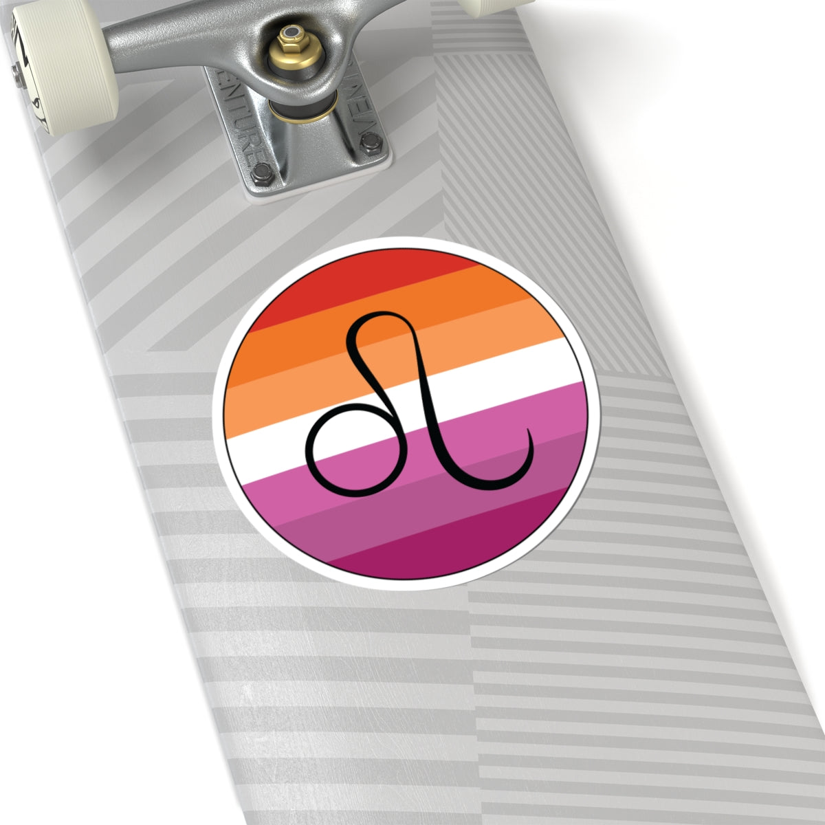 Close-up of the bottom of a silver skateboard featuring a 6 inch by 6 inch circular zodiac sticker with a centered Leo glyph on a Lesbian pride flag style background applied to the surface.