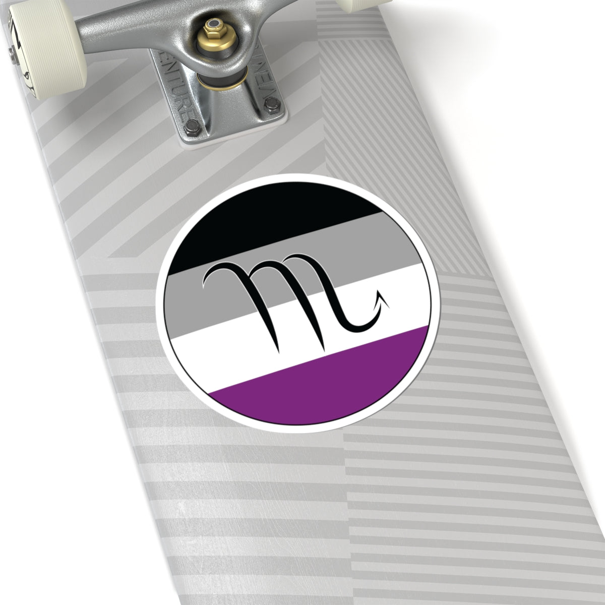 Close-up of the bottom of a silver skateboard featuring a 6 inch by 6 inch circular zodiac sticker with a centered Scorpio glyph on an Asexual pride flag style background applied to the surface.