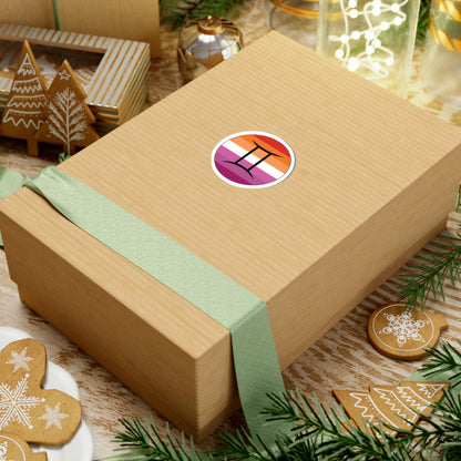Gift box with a green ribbon on a festive background with cookies and Christmas decorations. Gemini Lesbian pride sticker centered on the box.
